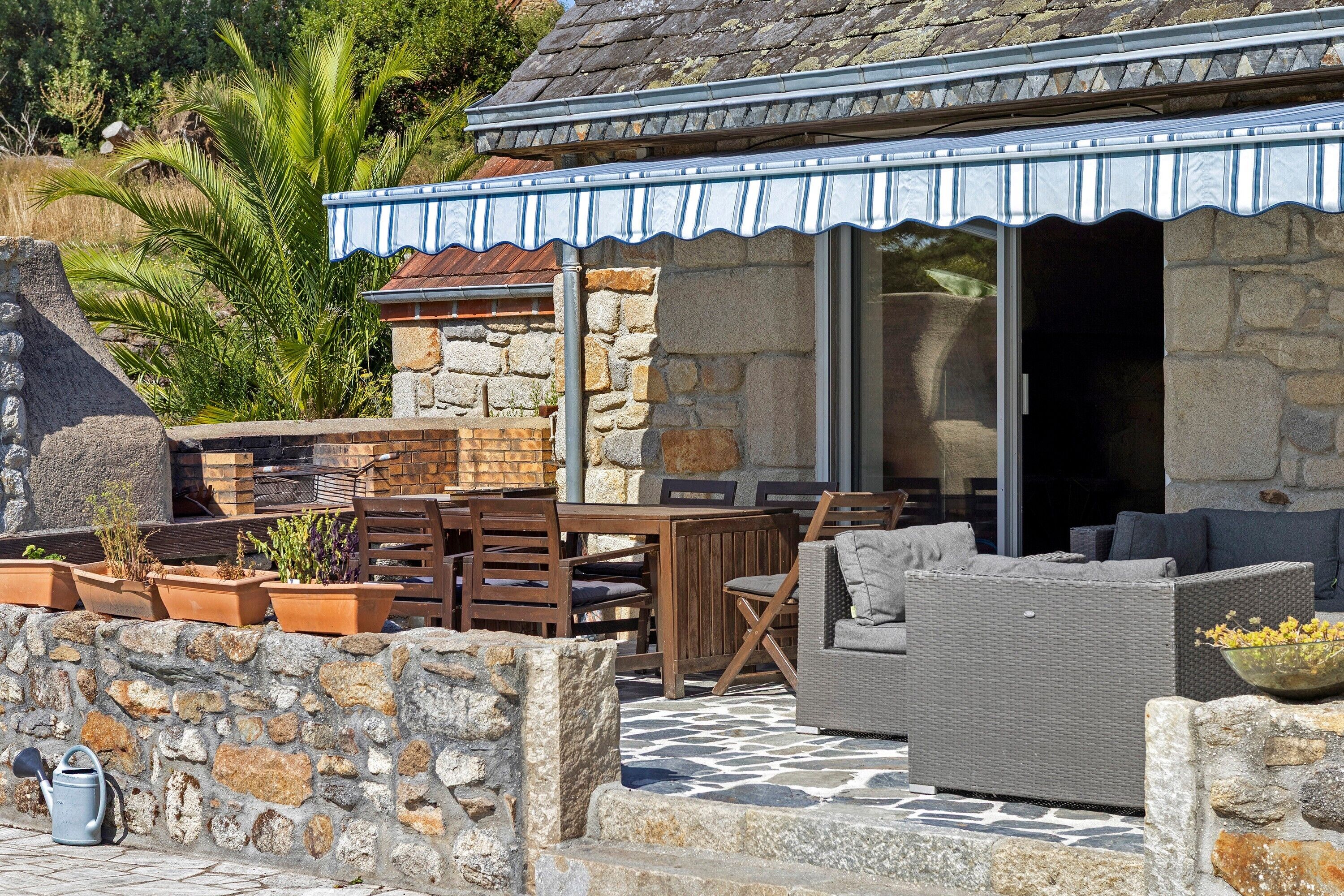 A patio area with a stone wall, wooden furniture, and a covered seating area.