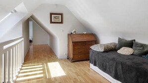 A bedroom with a sloped ceiling, wooden dresser, and a bed with pillows. - Holiday Home 'Maison Bringwiller Plage 200m' with Private Pool and Terrace (Trégastel)