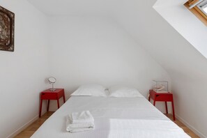A bedroom with a bed, two nightstands, a mirror, and a framed picture on the wall.