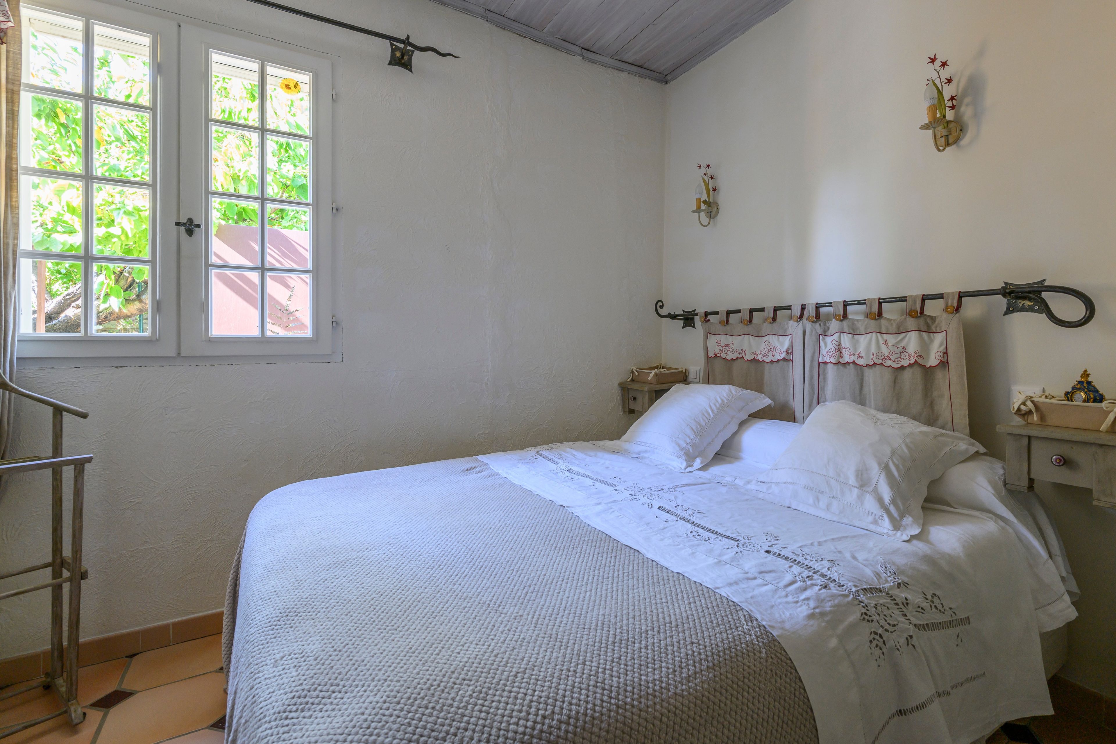 Ein Schlafzimmer mit Bett, Fenster, Nachttisch und Beistelltisch.