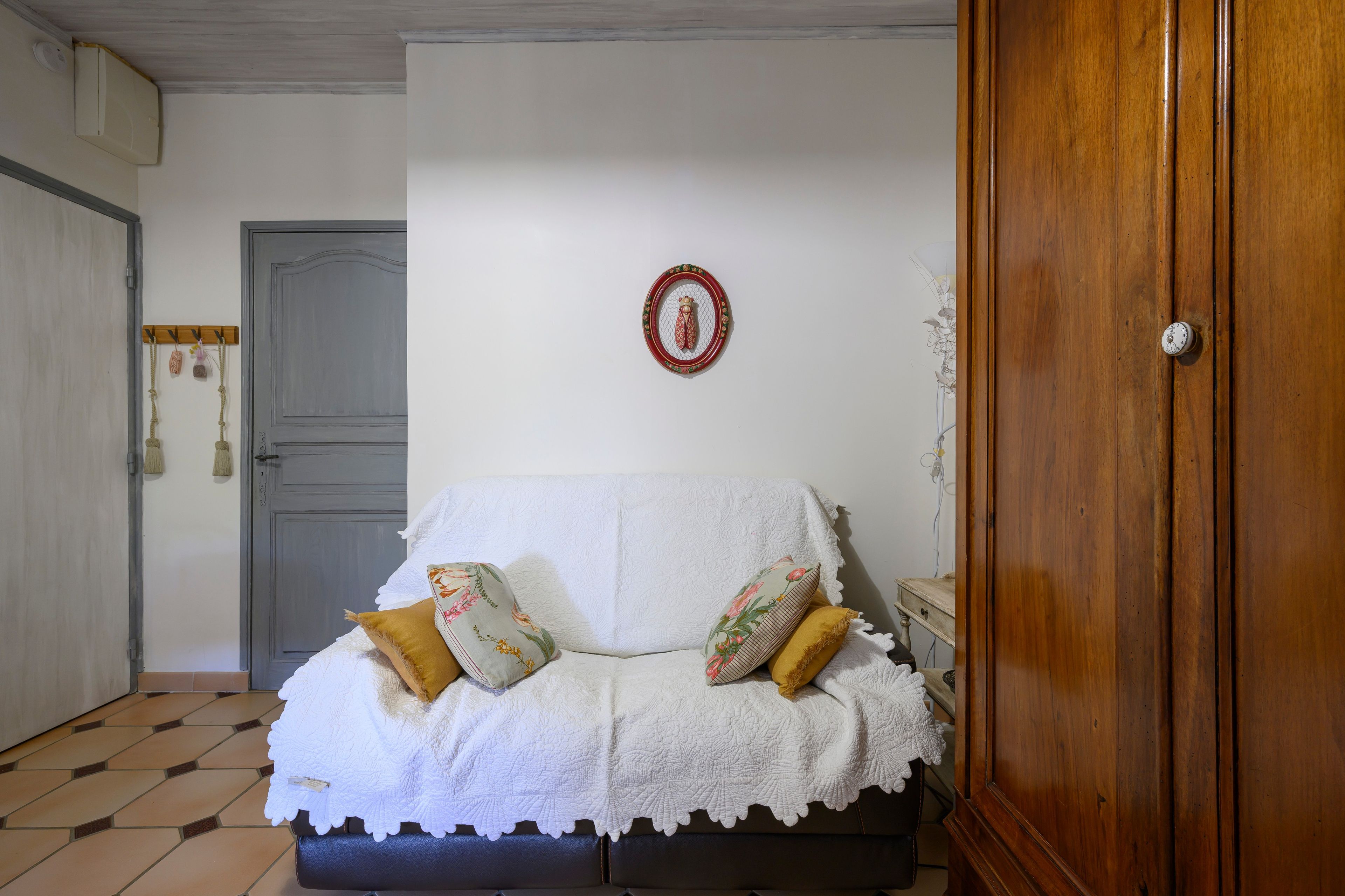 Une pièce comprenant un lit, une armoire en bois, une porte et un objet décoratif fixé au mur.