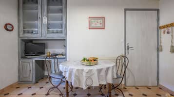 Een eetgedeelte met een ronde tafel, stoelen, een televisie en een kast.