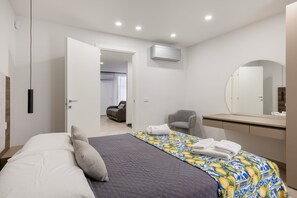 A modern hotel room with a bed, a desk, and a chair.