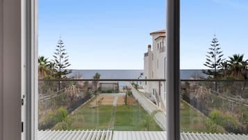 Ein Balkon mit Blick auf eine Küstenlandschaft, inklusive eines Gebäudes mit einem Turm und einem klaren Himmel.