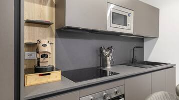 A compact kitchen with a built-in microwave, a coffee machine, and a sink.