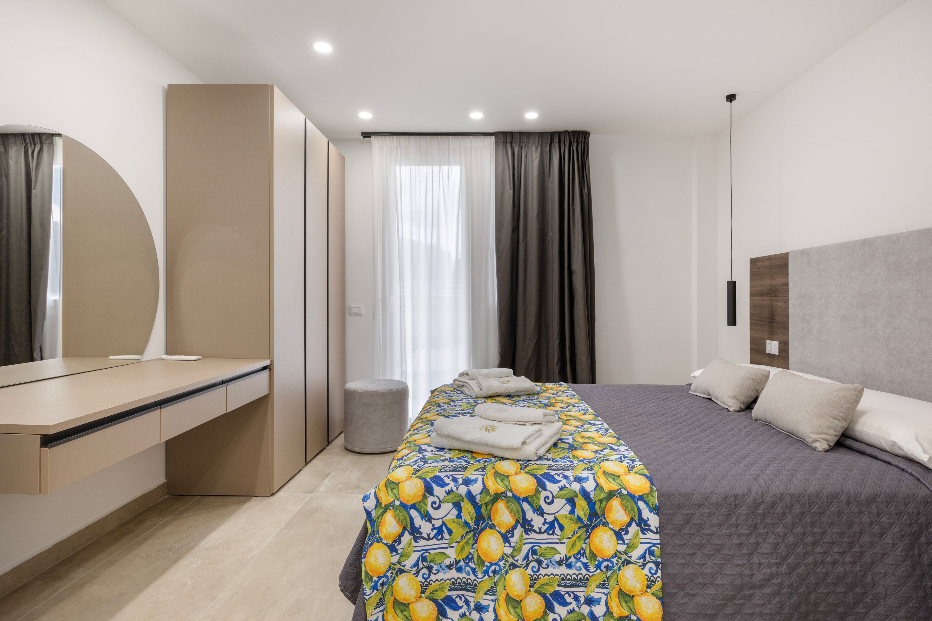 Une chambre d’hôtel moderne, équipée d’un lit, d’une table de chevet et d’un grand miroir.