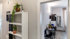 Une chambre d’hôtel moderne avec un coin repas, une plante en pot, un miroir et un téléviseur.
