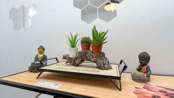 Una mesa con superficie de madera, una estatua de Buda, un cactus y una figurita de Buda.