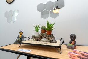 A table with a wooden surface, a Buddha statue, a cactus, and a Buddha figurine.