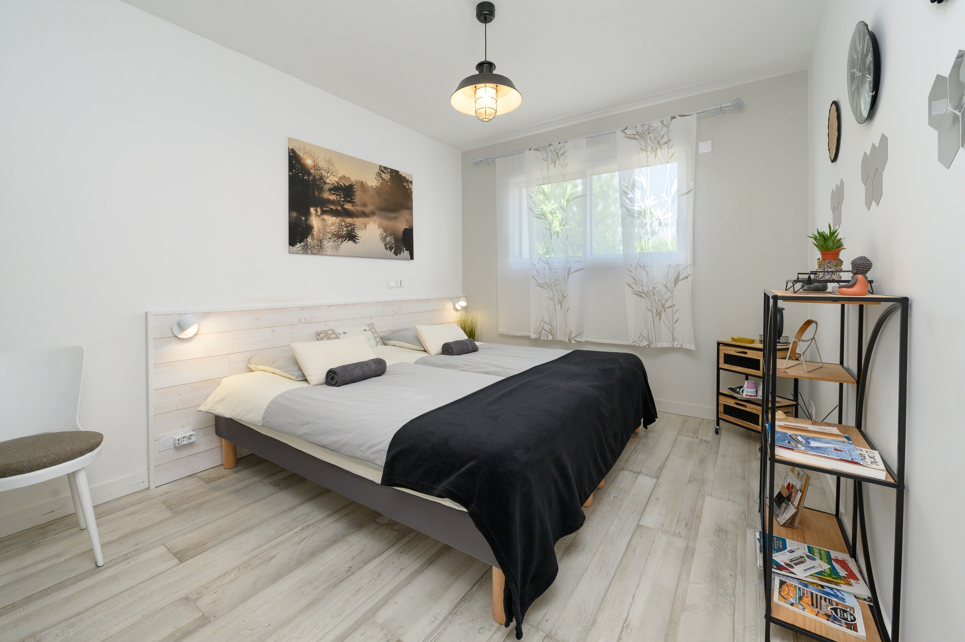 A modern bedroom with a bed, bedside tables, a chair, and a window with curtains.