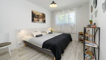 A modern bedroom with a bed, bedside tables, a chair, and a window with curtains.