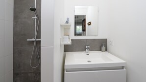 Un baño moderno con ducha, lavamanos y espejo.