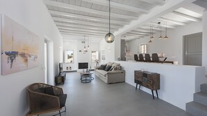 Ein großzügiger Wohnbereich mit hohen Decken, einer Couch, einem Couchtisch und einem Essbereich mit Stühlen.
