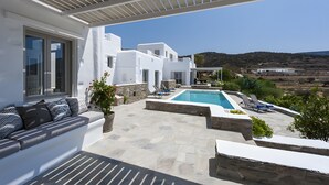 Eine weiße Villa mit Pool, Steinböden und Blick auf die Landschaft.