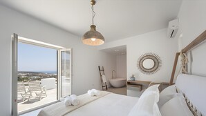 Ein Schlafzimmer mit einem großen Bett, Blick durch eine Schiebetür, einem Badezimmer mit einer Badewanne und einer Deckenleuchte.