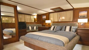Quarto com cama grande, mesas de cabeceira, televisão e espelho.