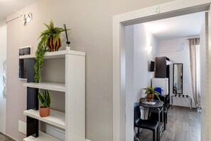 Camera d'albergo moderna con zona pranzo, una pianta in vaso, uno specchio e una TV.