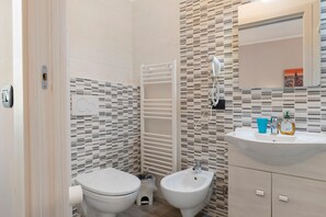 A bathroom with a toilet, bidet, and a sink with a mirror.