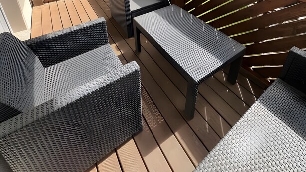 A wooden deck with outdoor furniture, including wicker sofas and a table, overlooking a garden and neighboring houses. - Apartment "New Holiday Home for 2 Guests" with Shared Garden, Balcony & Wi-Fi (Oelsnitz/Erzgebirge)
