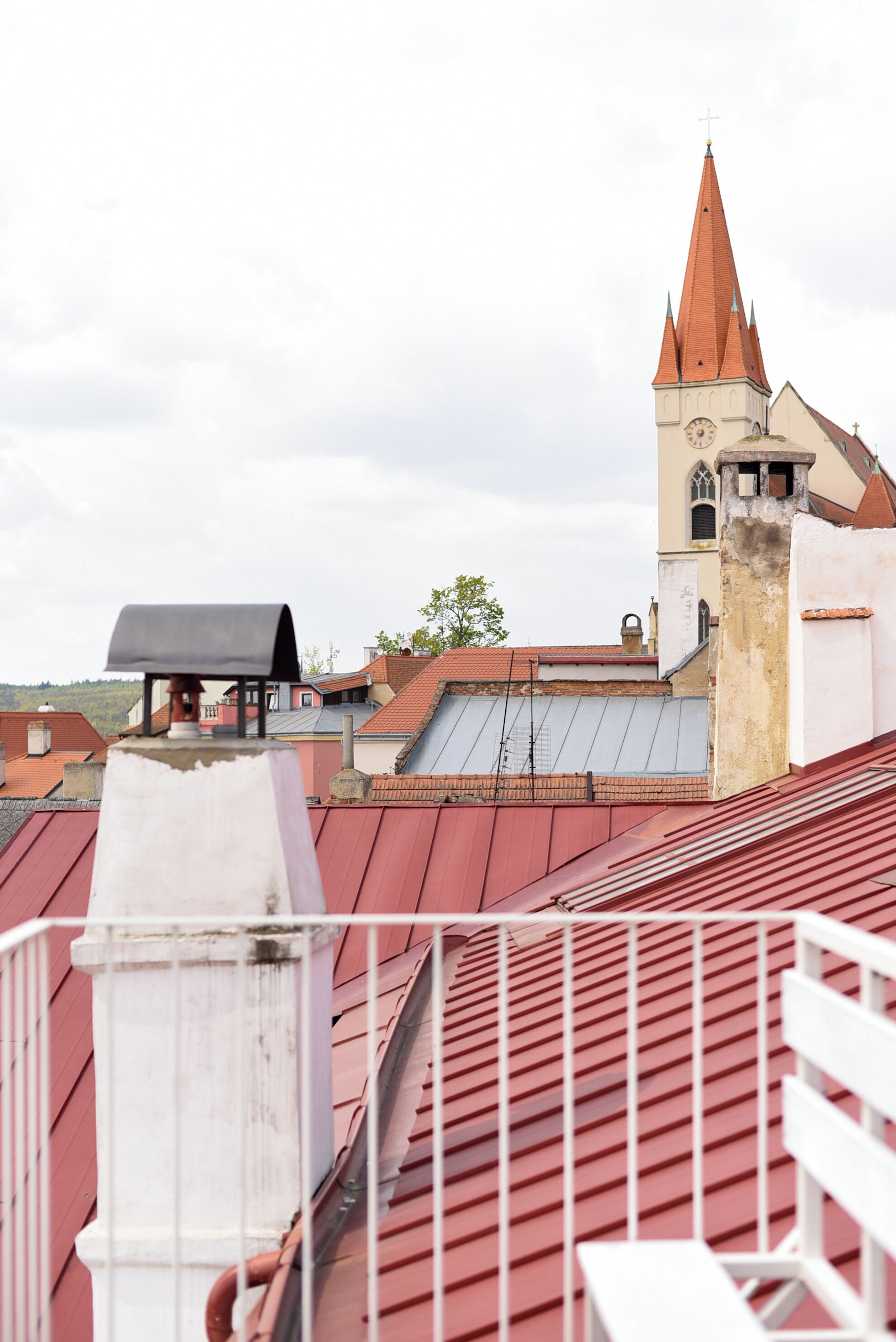Ein Gebäude mit rotem Dach, einem Turm mit Kreuz und einem Glockenturm.