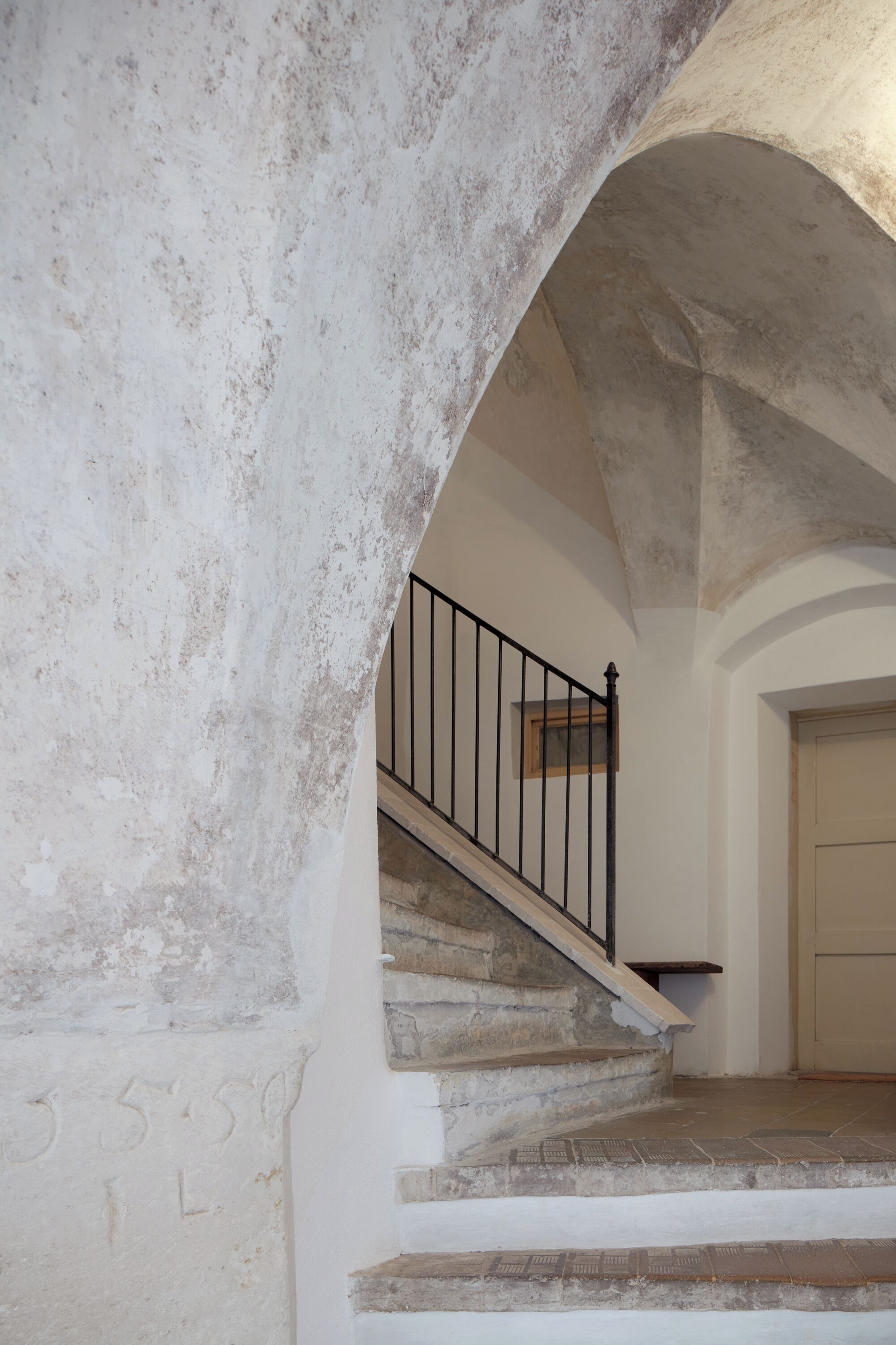 A stone staircase with a metal railing leading to a door.