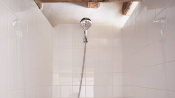 A shower with a wooden ceiling beam, white tiled walls, and a chrome showerhead.