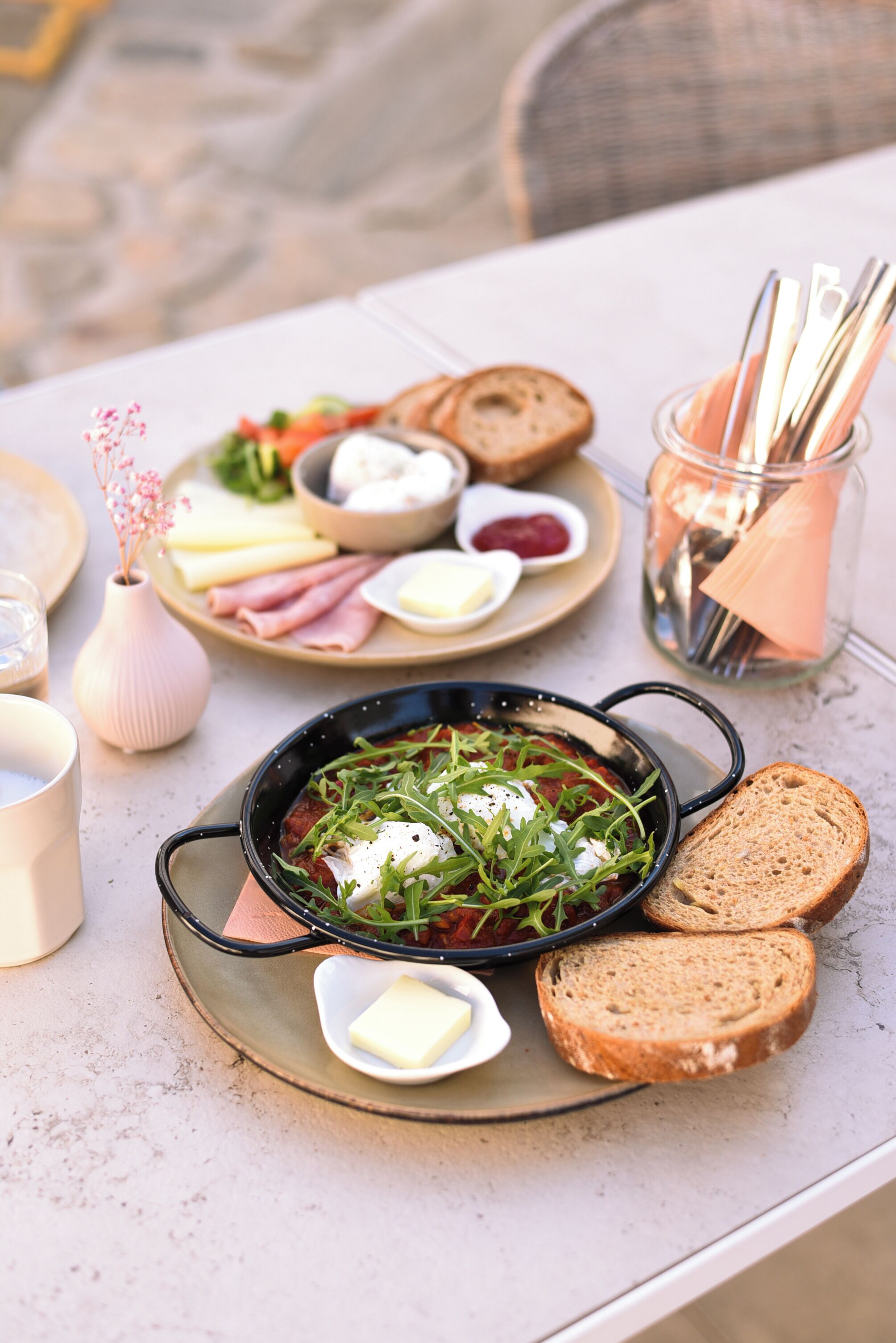 Uma mesa de jantar com diversos alimentos, incluindo p ão, queijo e um prato com vegetais e ovos.