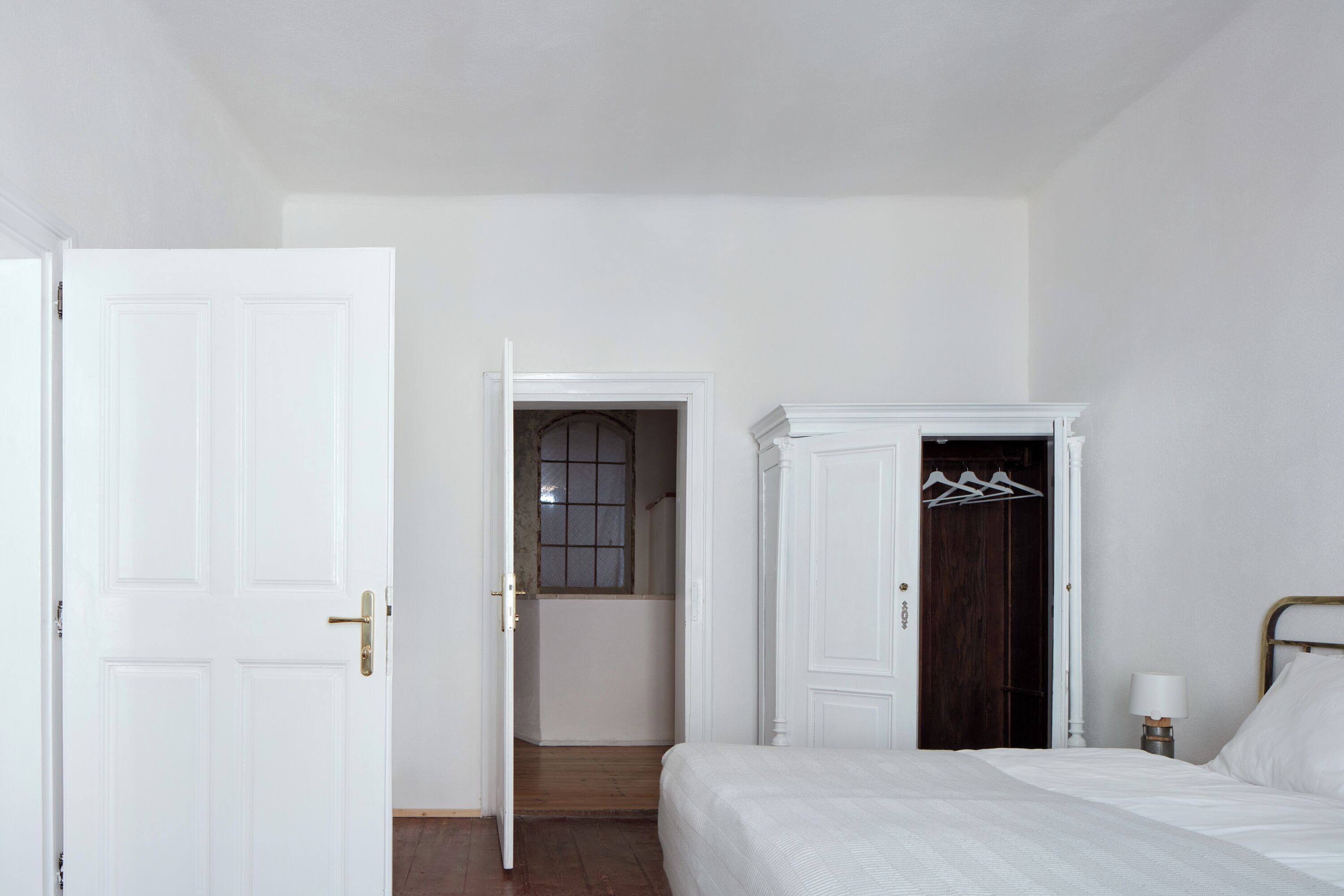 Un dormitorio con cama, armario, puerta y ventana.