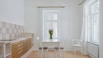 Et køkken med spisebord, stole, et vindue med gardin og en radiator.