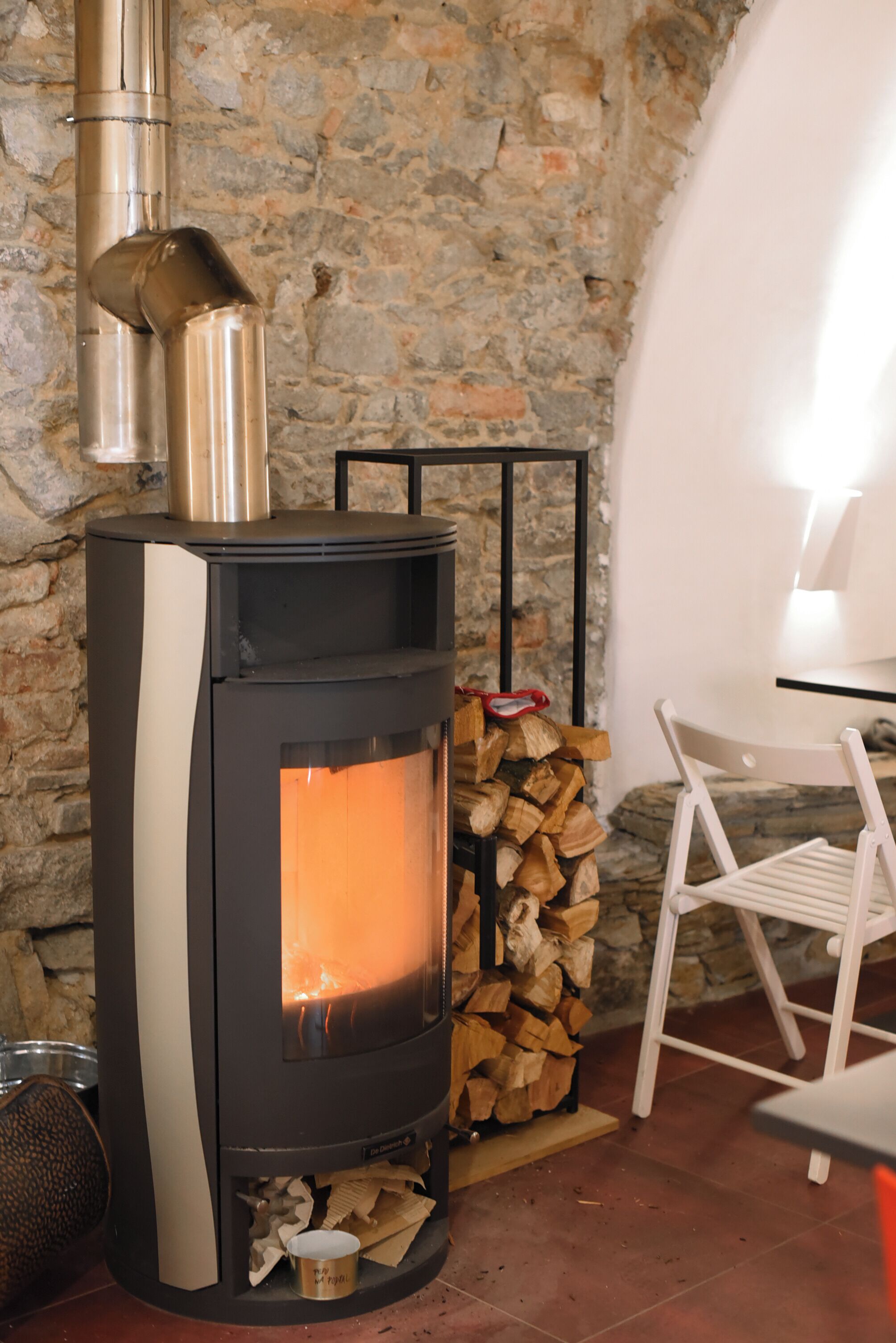 A stone wall, a wood-burning stove, a chair, and a table.