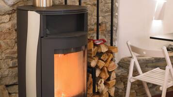 A stone wall, a wood-burning stove, a chair, and a table.