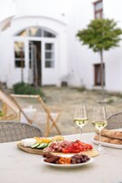 Una tabla de embutidos, dos copas de vino blanco y pan.
