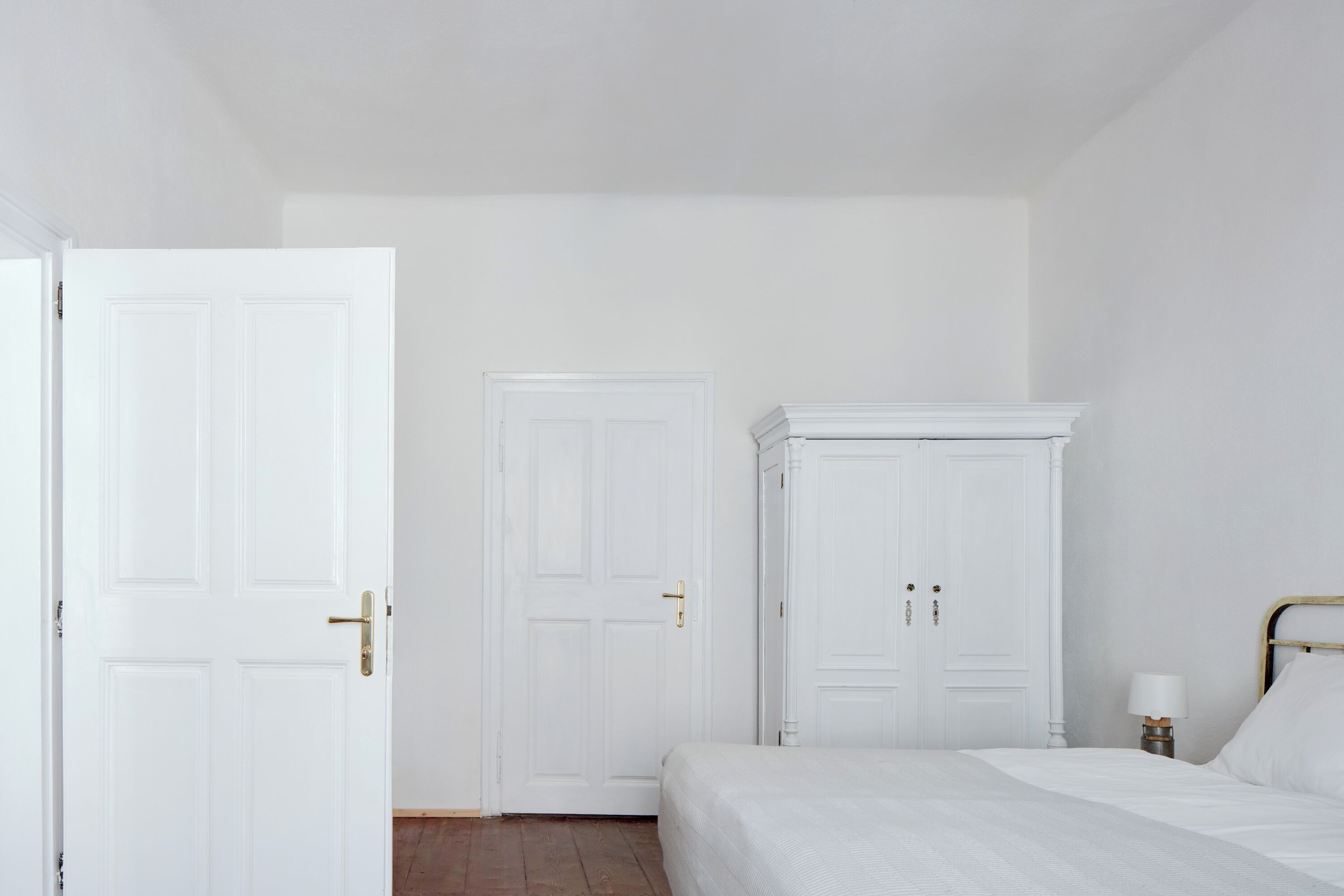 A bedroom with a bed, a wardrobe, and a door.