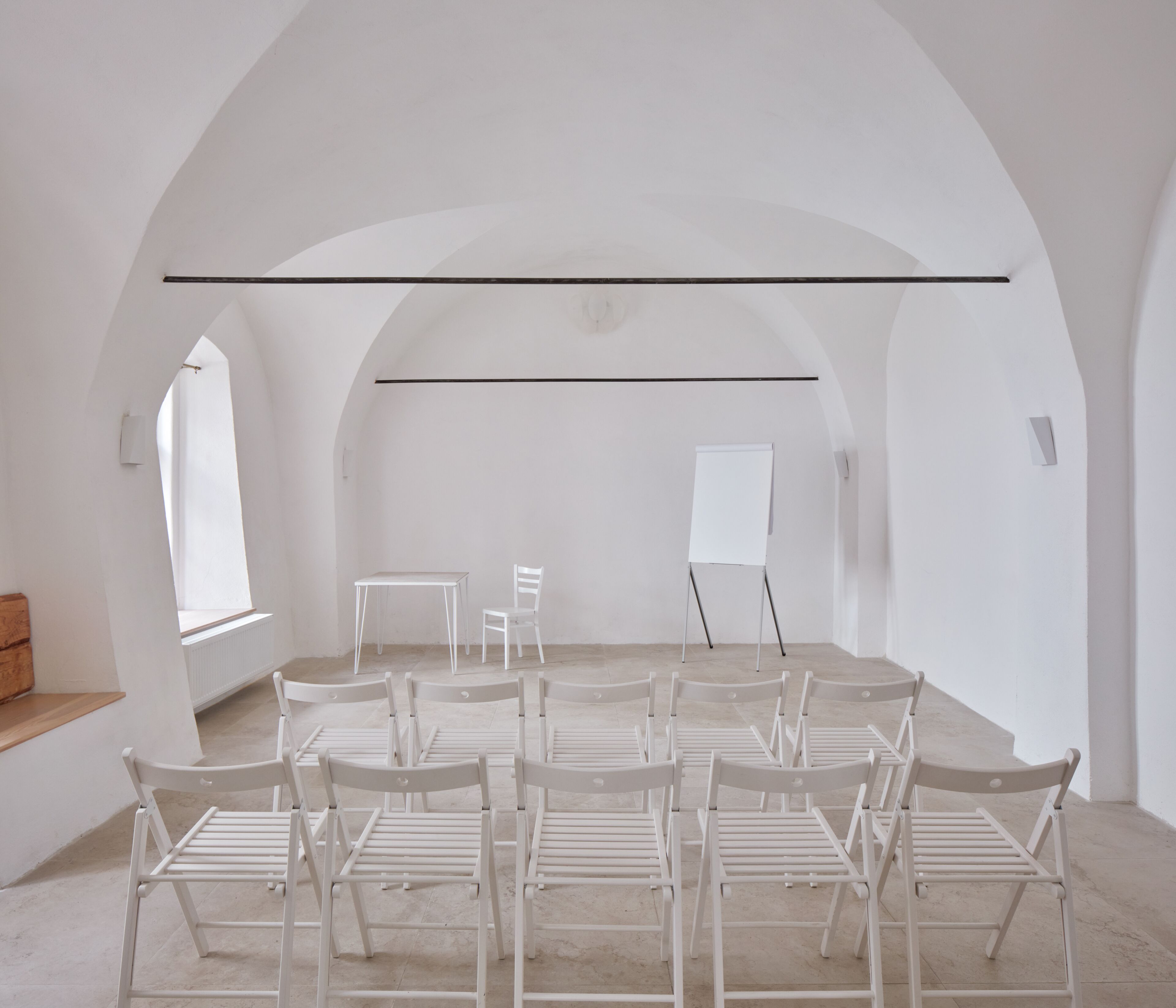 Une pièce avec une longue table, plusieurs chaises, un tableau blanc et une fenêtre.