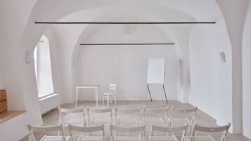 Une pièce avec une longue table, plusieurs chaises, un tableau blanc et une fenêtre.