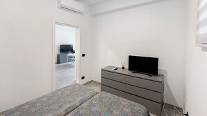 Ein Schlafzimmer mit Bett, Kommode, Fernseher und Klimaanlage.