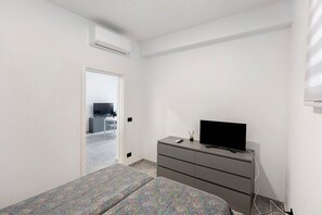 A bedroom with a bed, a dresser, a TV, and an air conditioning unit. - Apartment 'Via Leucosia' with Sea View, Wi-Fi and Air Conditioning (Salerno)
