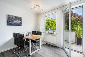 Ein Essbereich mit Tisch, Stühlen und Blick durch eine Glastür in einen Garten.