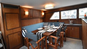 A dining area with a long table set for six, wooden paneling, and a view through the window.