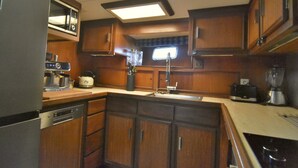 A compact kitchen with wooden cabinets, a built-in microwave, a sink, and a stove.