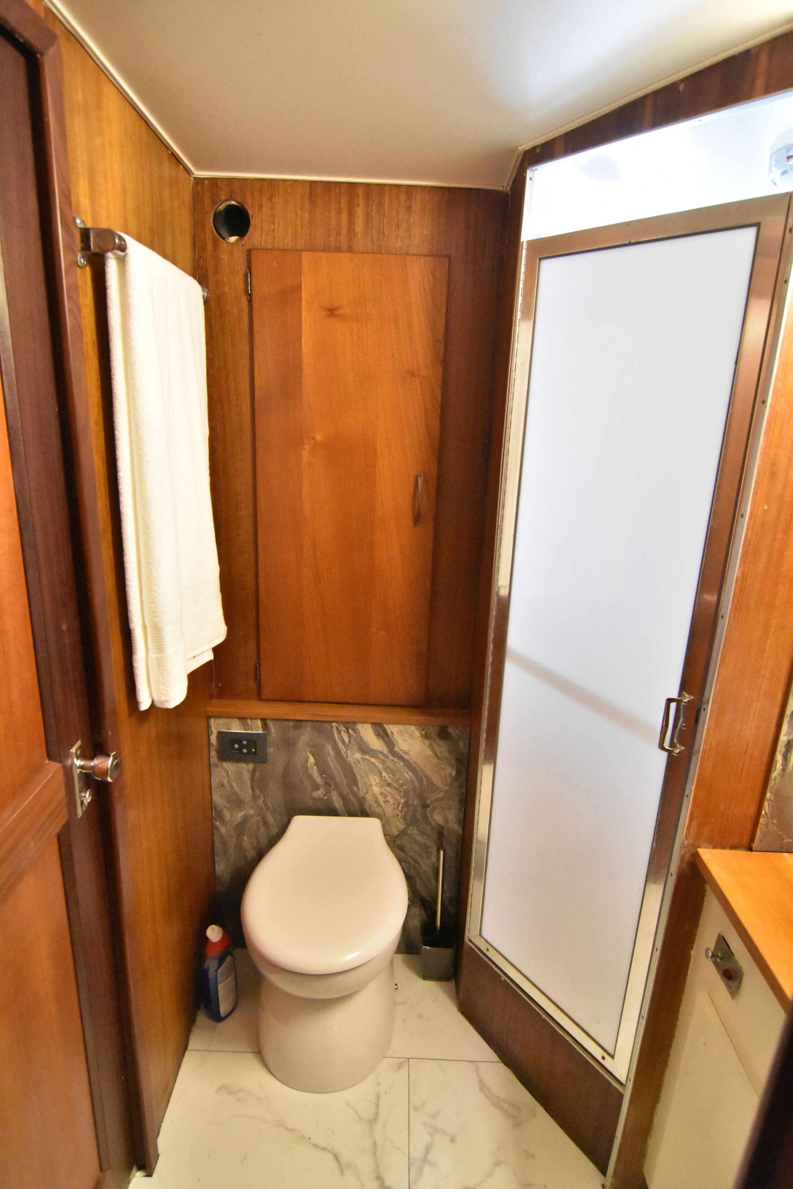 Ein kleines Badezimmer mit Toilette, einer Duschkabine und einem Holzbadezimmermöbel.