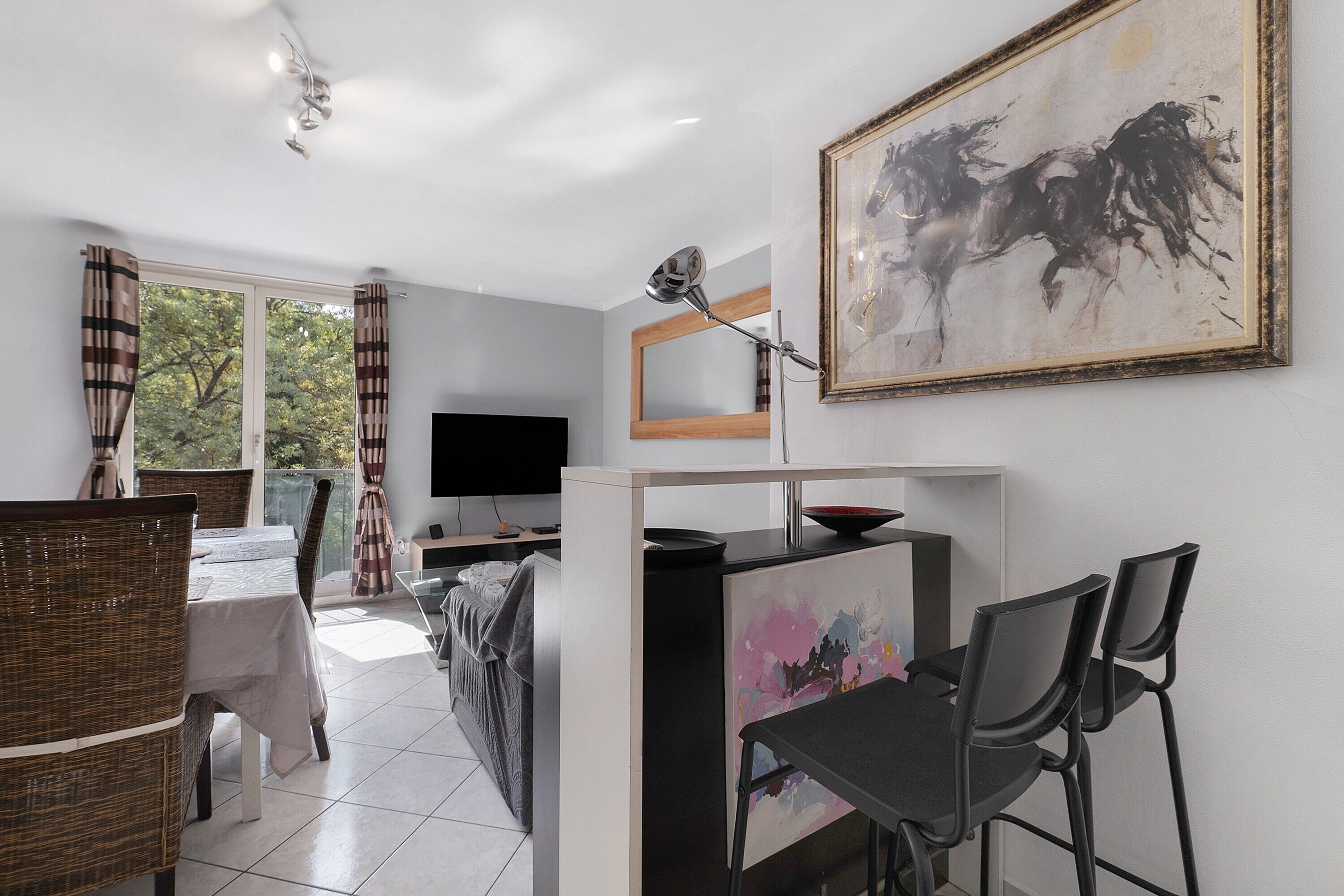 Una sala de estar moderna con comedor, un cuadro grande en la pared y un televisor.