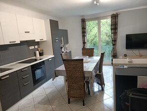 Eine moderne Küche mit Essbereich, einem Fernseher und einem Balkon mit Vorhängen.