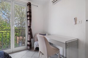 Een kamer met een schuifdeur, een wit bureau, een stoel en een klein tafeltje met een plaid.