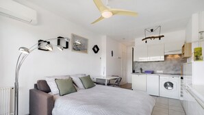 A modern bedroom with a bed, a desk, a chair, a washing machine, and a ceiling fan. - Studio "Le Kennedy Bord De Mer" with Balcony, Wi-Fi and Air Conditioning (Cagnes-sur-Mer)