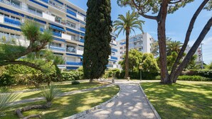 A pathway leading to a building with multiple balconies, surrounded by well-maintained greenery and trees. - Studio "Le Kennedy Bord De Mer" with Balcony, Wi-Fi and Air Conditioning (Cagnes-sur-Mer)