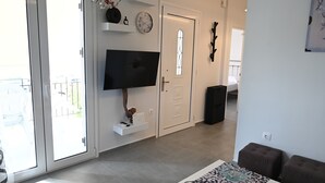 Ein modernes Wohnzimmer mit einem Flachbildfernseher, einer Glastür und einer Treppe, die zu einer anderen Ebene führt.