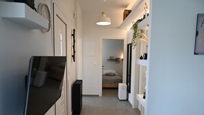 Ein schmaler Flur mit einem Bett, einem kleinen Tisch und einem Fernseher.