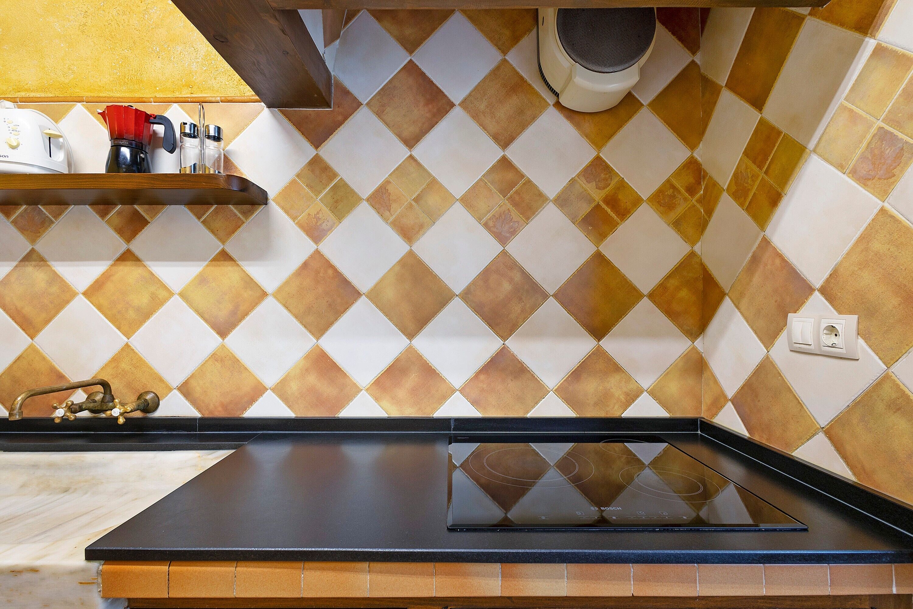 Una cocina con encimera negra, estufa y salpicadero con diseño de diamantes.
