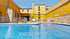 Une piscine aux murs recouverts de carreaux et dont un des côtés est constitué d’une structure en pierre.